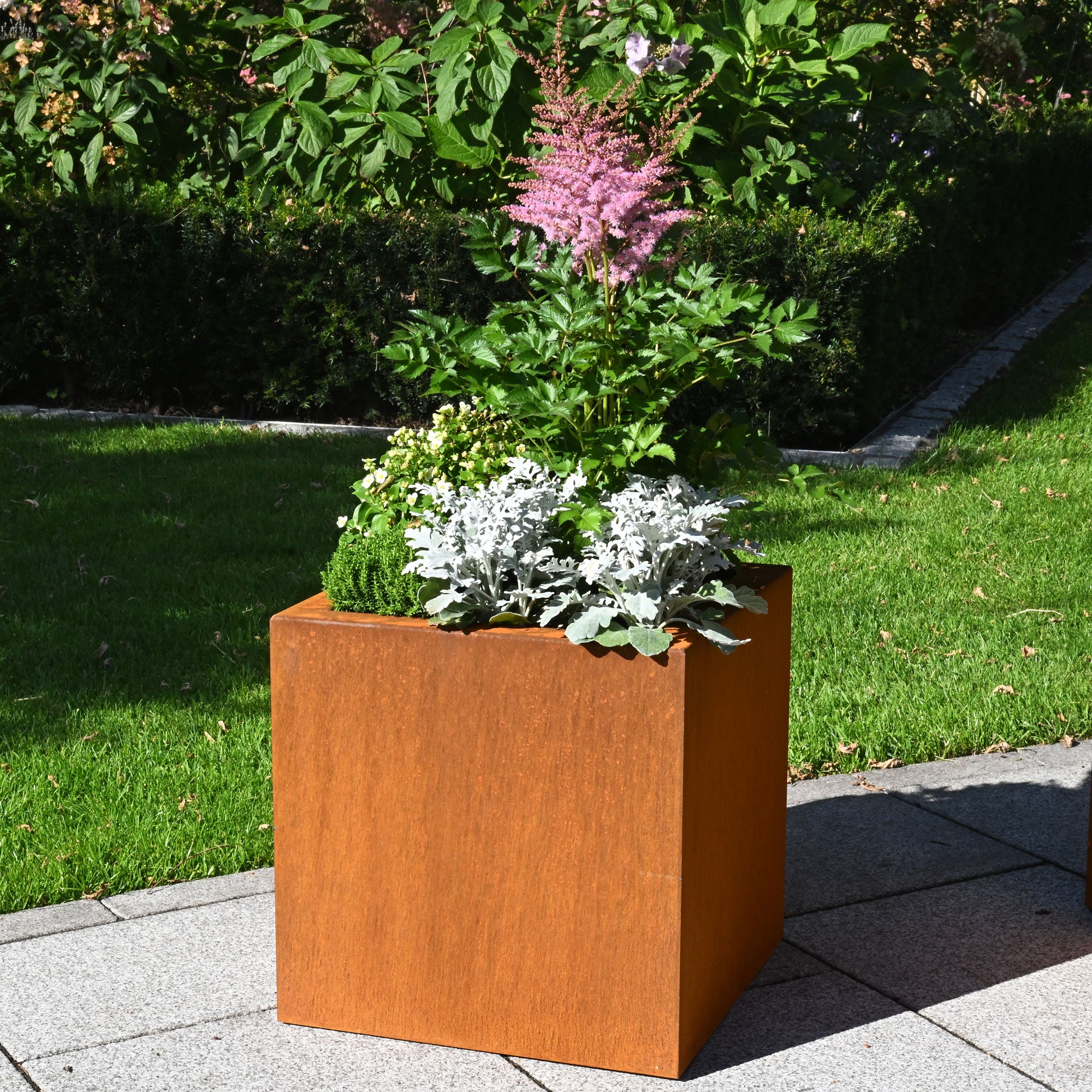 Pflanzkübel aus Cortenstahl im Garten mit Blumen bepflanzt
