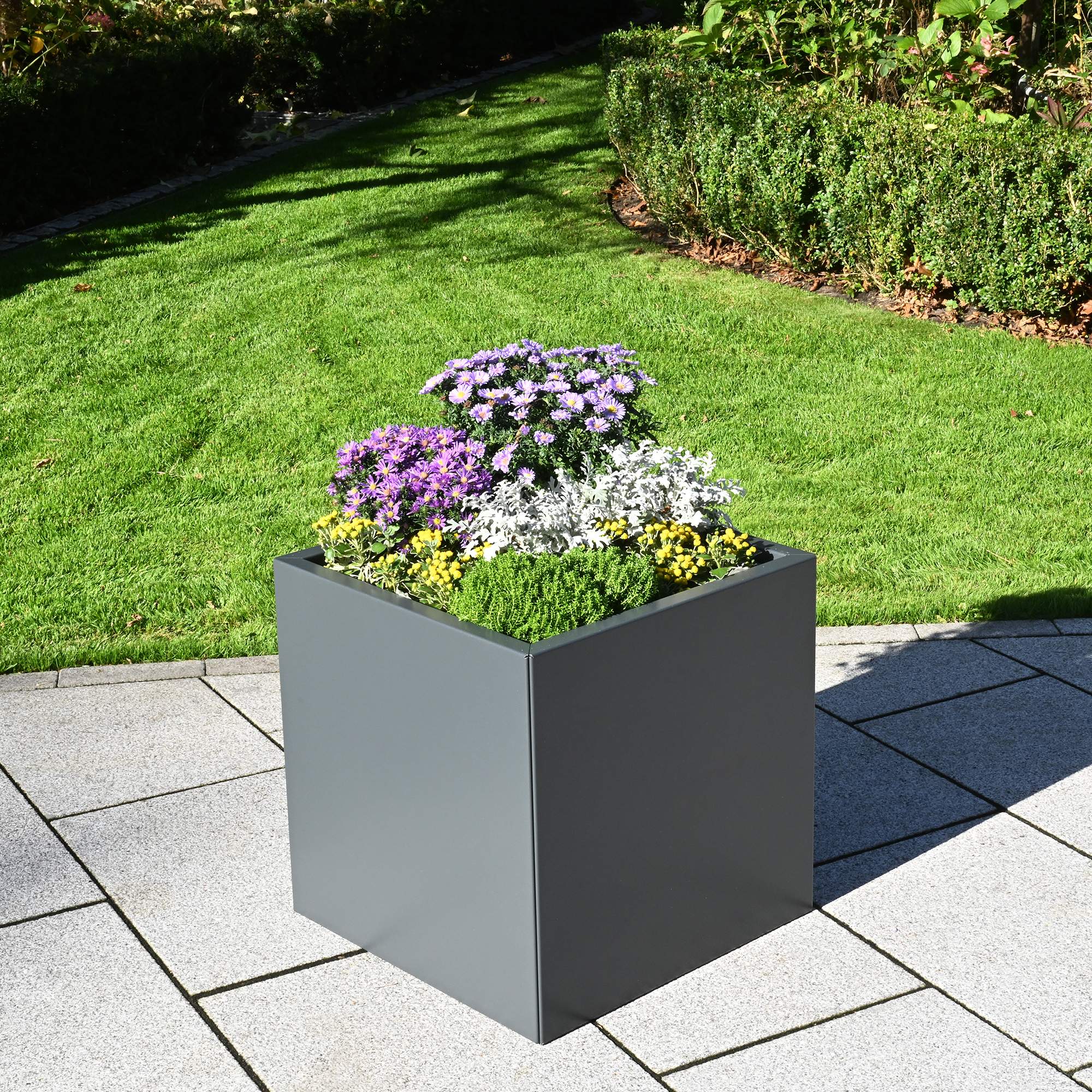 Grauer Aluminium-Pflanzkasten Duplex mit bunten Blumen auf einer Terrasse vor dem Garten