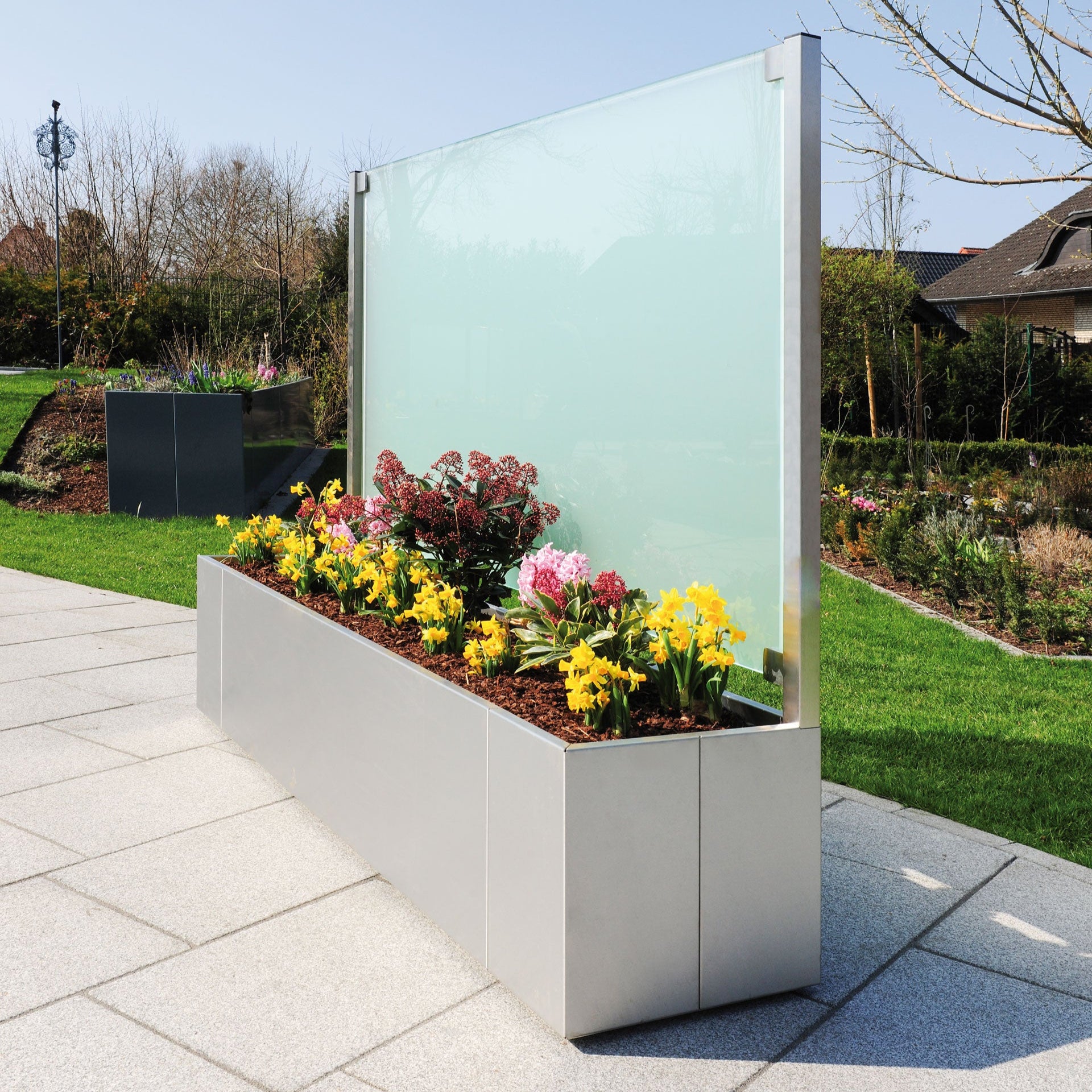 Sichtschutz aus Edelstahl mit Pflanzkasten und trüber Glasscheibe aus Milchglas auf der Terrasse